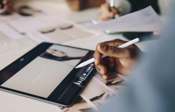 Close-up of a man working on digital tablet on meeting table. Processing photos on a tablet computer for their project in a meeting.